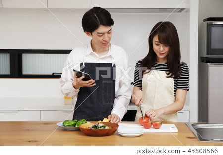 Couple searching the net with a tablet on the tablet and cooking Couple searching the net with a tablet on the tablet and cooking 43808566