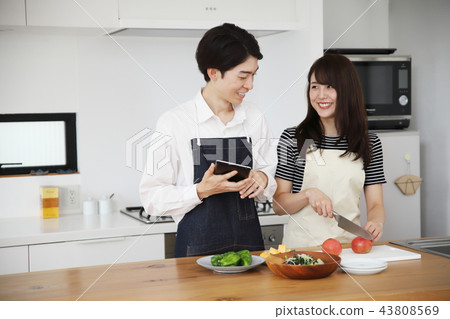 Couple searching the net with a tablet on the tablet and cooking Couple searching the net with a tablet on the tablet and cooking 43808569