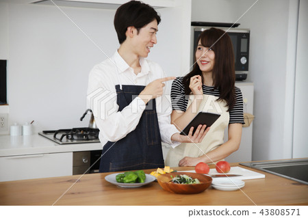 Couple searching the net with a tablet on the tablet and cooking Couple searching the net with a tablet on the tablet and cooking 43808571