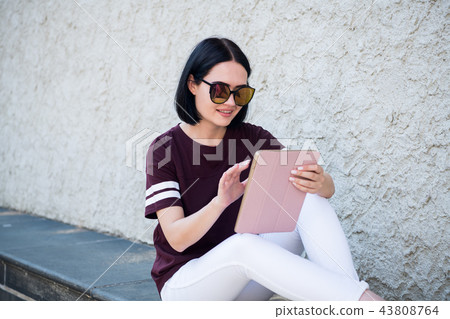 closeup of happy woman in glasses using tablet pc in the street 43808764