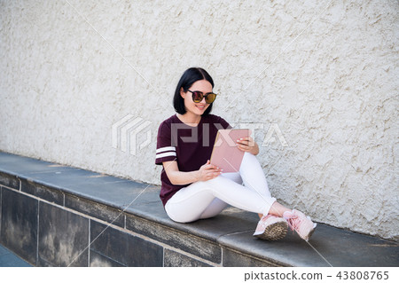 Happy woman in glasses using tablet pc in the street Happy woman in glasses using tablet pc in the street 43808765