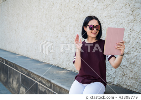 Smiling millennial girl talking by videocall looking at camera, female teen video blogger recording Smiling millennial girl talking by videocall looking at camera, female teen video blogger recording 43808779