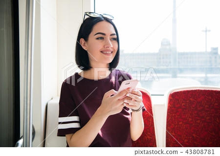 Young happy woman sitting in city bus and using her mobile phone. 43808781