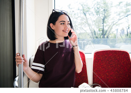 Young happy woman sitting in city bus and talking on mobile phone. Young happy woman sitting in city bus and talking on mobile phone. 43808784