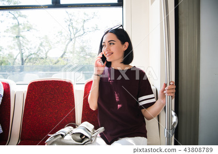 Young happy woman sitting in city bus and talking on mobile phone. Young happy woman sitting in city bus and talking on mobile phone. 43808789