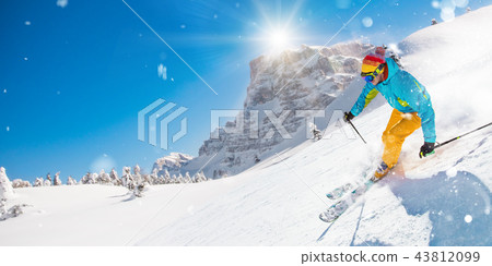 Skier skiing downhill in high mountains 43812099