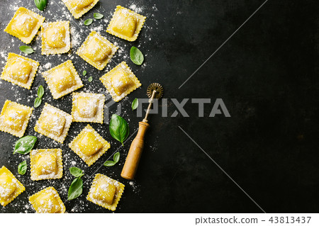 Raw ravioli with basil and flour on dark Raw ravioli with basil and flour on dark 43813437