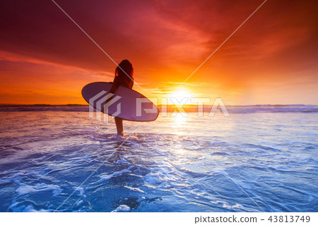 Surfer woman on beach at sunset Surfer woman on beach at sunset 43813749