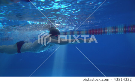 Beautiful professional swimmer doing butterfly stroke in pool with rich blue water, shot from 43814322