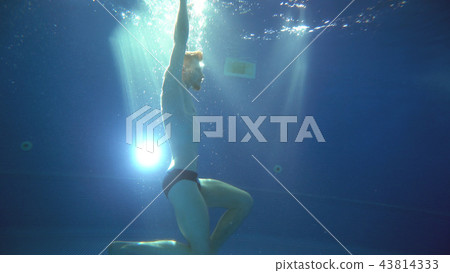 A young man somersaults and does a somersault under the water. He is posing in front of the camera A young man somersaults and does a somersault under the water. He is posing in front of the camera 43814333