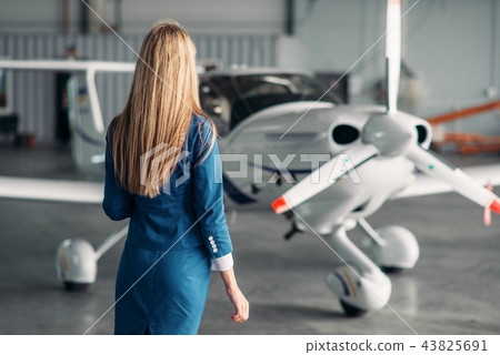 Stewardess against turboprop airplane in hangar 43825691