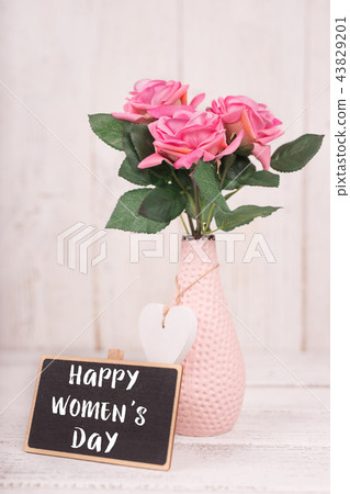 Small chalkboard for Women's day. Background with pink roses in vase. 43829201