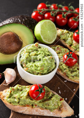 A delicious bowl of Guacamole with fresh ingredients on stone table. 43829468