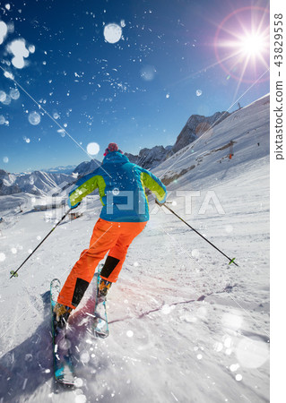 Skier on piste running downhill in beautiful Alpine landscape. Blue sky on background. Skier on piste running downhill in beautiful Alpine landscape. Blue sky on background. 43829558
