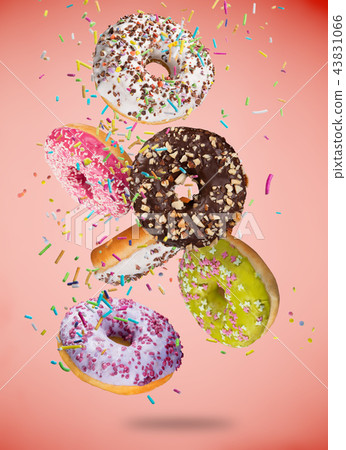 Tasty doughnuts in motion falling on pastel red background. Tasty doughnuts in motion falling on pastel red background. 43831066