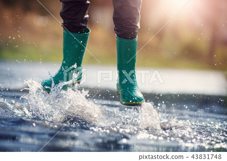 Child walking in wellies in puddle on rainy weather 43831748