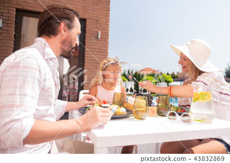 Joyful positive woman offering her daughter a tomato Joyful positive woman offering her daughter a tomato 43832869