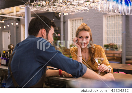 Cute girl leaning on the bar counter and flirting with barman 43834212