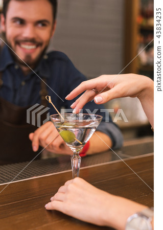 Young barman smiling and the client touching the glass Young barman smiling and the client touching the glass 43834235