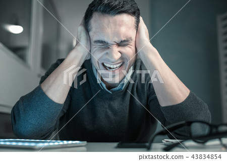 Upset young man squeezing head with hands Upset young man squeezing head with hands 43834854