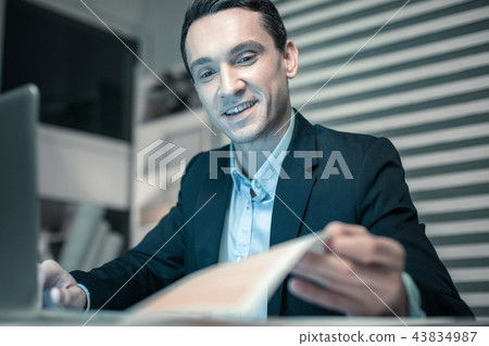 Smiling business man watching at his notebook Smiling business man watching at his notebook 43834987