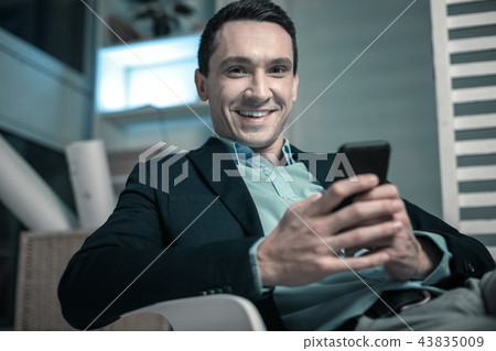 Pleasant business man texting a message on his phone 43835009