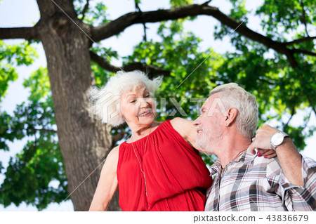 Kind pensioner looking at his wife standing high and smiling to him Kind pensioner looking at his wife standing high and smiling to him 43836679