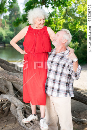 Happy senior woman standing on the log and looking at her husband Happy senior woman standing on the log and looking at her husband 43836701