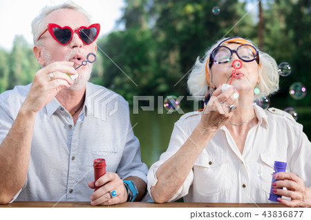 Funny pensioners wearing sunglasses and blowing soap bubbles 43836877