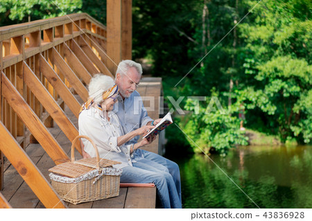 Smiling senior couple leaning to each other and looking at notebook Smiling senior couple leaning to each other and looking at notebook 43836928