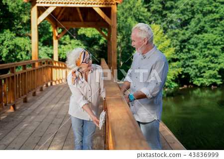 Positive pensioners smiling while placing heart symbol on the bridge 43836999