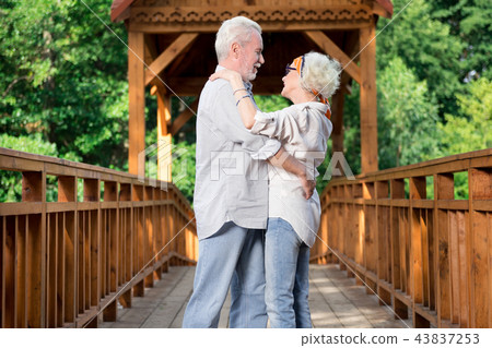 Adorable aged couple dancing while being on the bridge Adorable aged couple dancing while being on the bridge 43837253