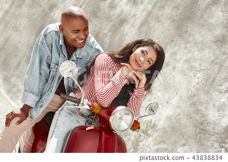 Active Lifestyle. Young diverse couple sitting on bike on the city street smiling relaxed 43838834