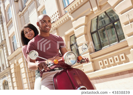 Romantic Relationship. Young diverse couple riding bike on the city street together smiling happy Romantic Relationship. Young diverse couple riding bike on the city street together smiling happy 43838839