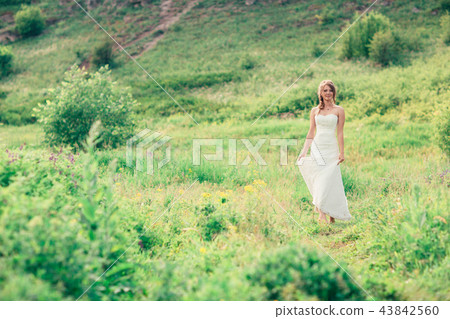bride stands on a background of grass and mountain 43842560