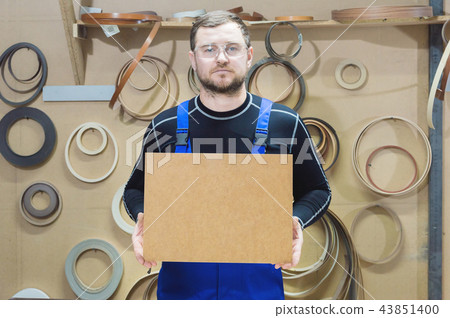 The manufacturer of furniture in special clothes and goggles keeps an empty plate for the text while 43851400