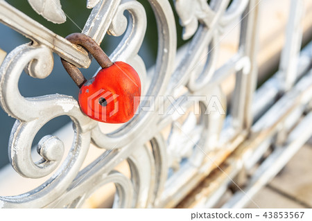 Red heart padlock locked on fence. Lock in shape of heart as symbol of eternal love Red heart padlock locked on fence. Lock in shape of heart as symbol of eternal love 43853567