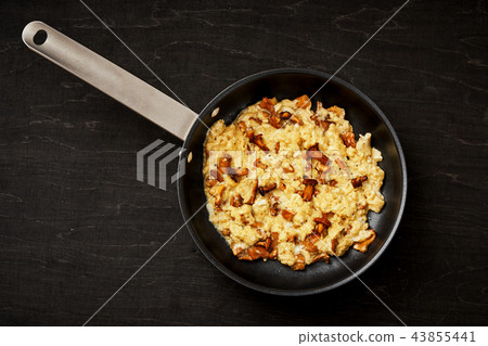 scrambled eggs with chanterelles straight from the forest in a pan on a wooden kitchen table 43855441