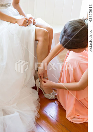 Bridesmaid Helping Bride Get Dressed For Wedding 43855618