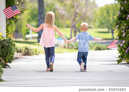 Sister and Brother Outdoors Waving American Flags Sister and Brother Outdoors Waving American Flags 43855883
