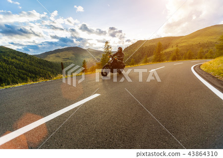 Motorcycle driver riding in Alpine highway, Nockalmstrasse, Austria, Europe. Motorcycle driver riding in Alpine highway, Nockalmstrasse, Austria, Europe. 43864310