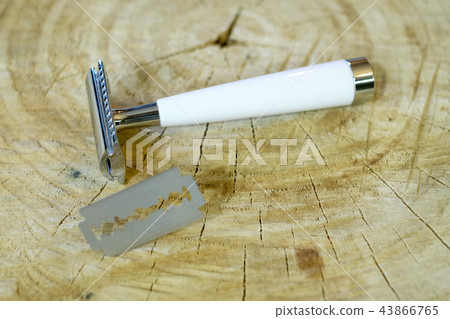 A traditional steel razor with a white bone handle and a steel razor blade on a natural wood A traditional steel razor with a white bone handle and a steel razor blade on a natural wood 43866765