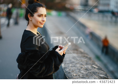 woman using her cell phone while walking through Paris 43871423