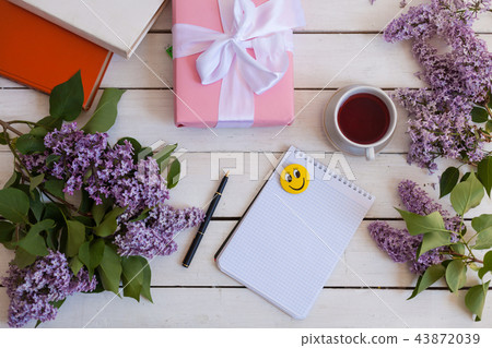 on the white table lilac, gift, notebook, cup of tea on the white table lilac, gift, notebook, cup of tea 43872039