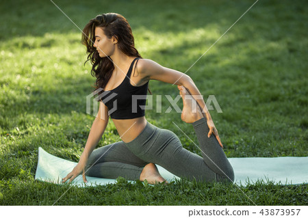 Woman practicing yoga outdoors in park Woman practicing yoga outdoors in park 43873957