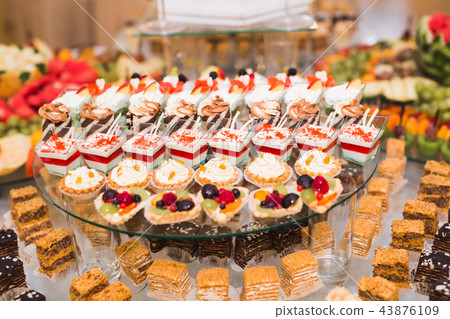 Delicious and tasty dessert table with cupcakes shots at reception closeup 43876109