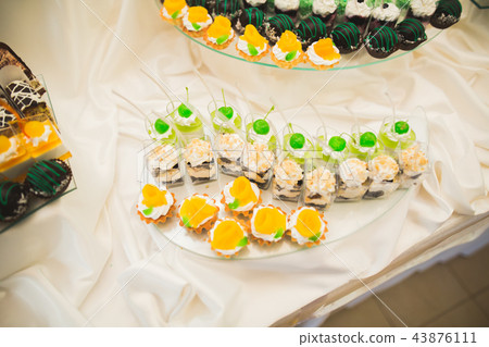Delicious and tasty dessert table with cupcakes shots at reception closeup Delicious and tasty dessert table with cupcakes shots at reception closeup 43876111