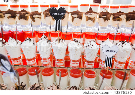 Delicious and tasty dessert table with cupcakes shots at reception closeup 43876180