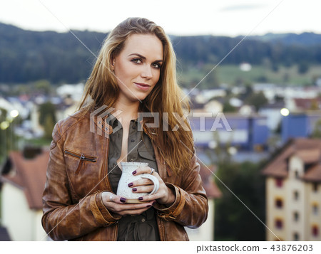 Beautiful young woman drinking coffee outdoors 43876203