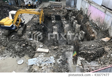 Concrete piles driven into ground by an excavator Concrete piles driven into ground by an excavator 43877477
